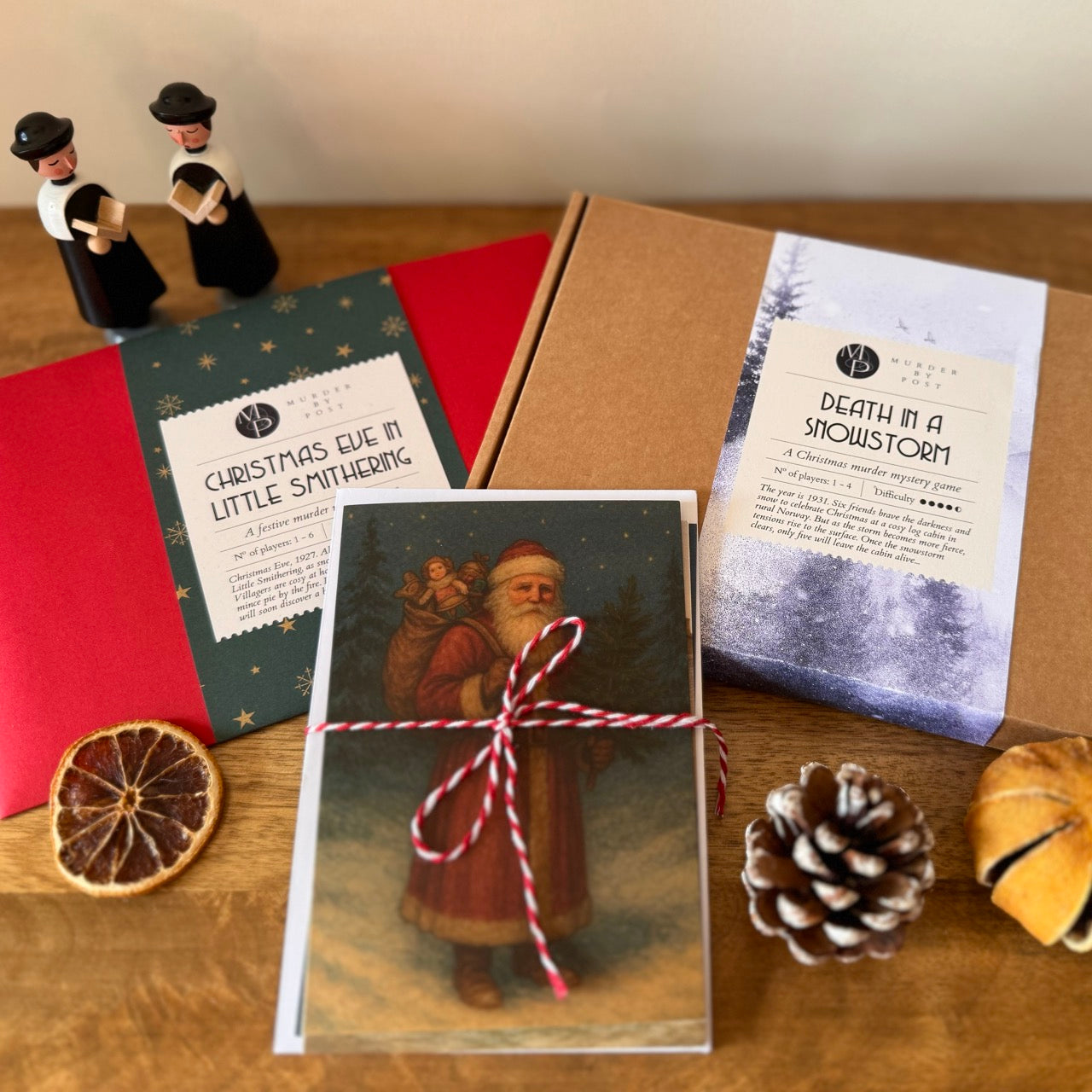 Christmas-themed murder mystery games and a vintage card set. Decorative elements, and a small figurine on a wooden surface.