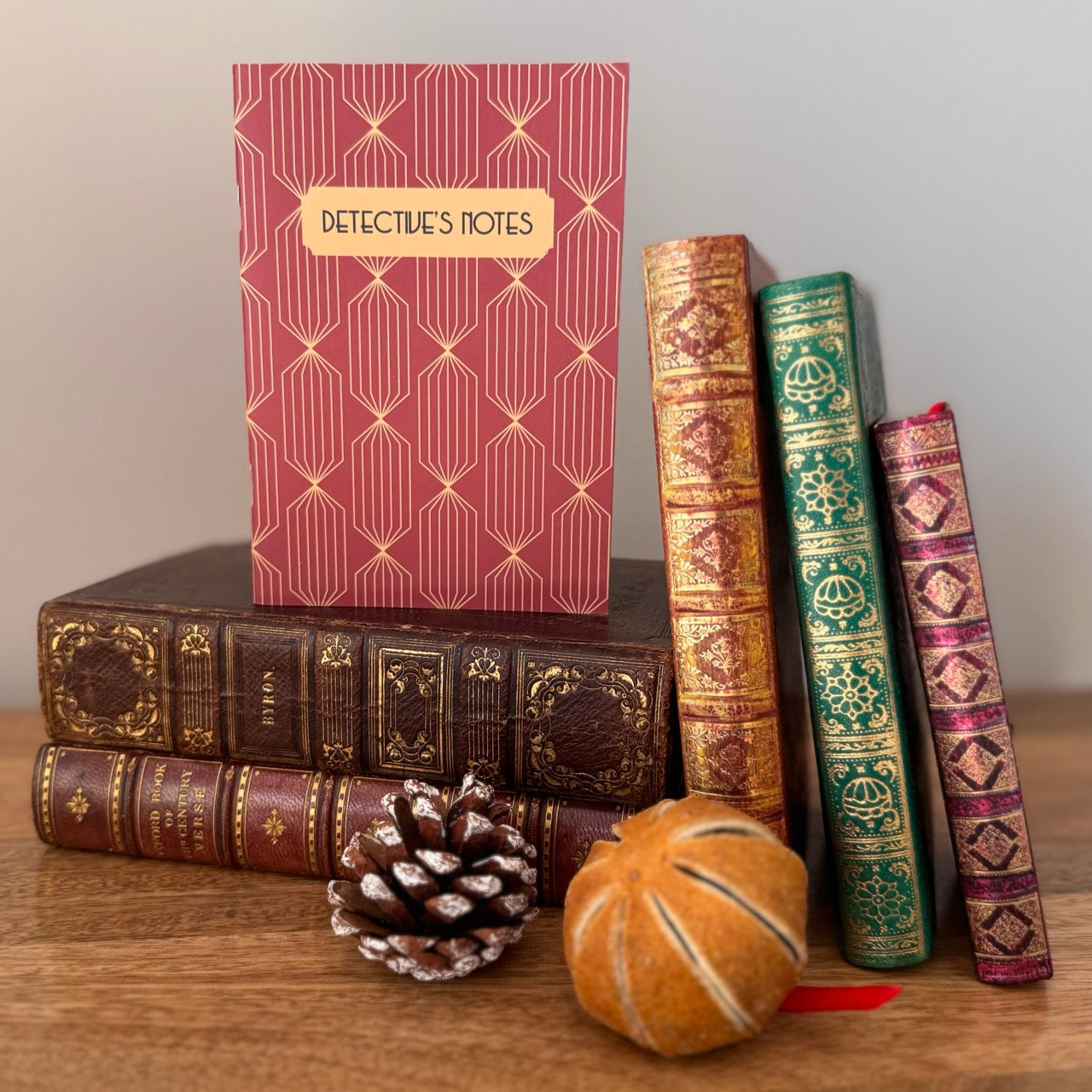 Decorative books with a 'Detective's Notes' notebook on a wooden surface.
