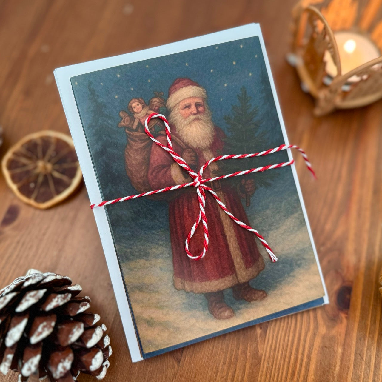 Vintage-style Christmas card set, Santa Claus on a wooden surface with decorative elements.