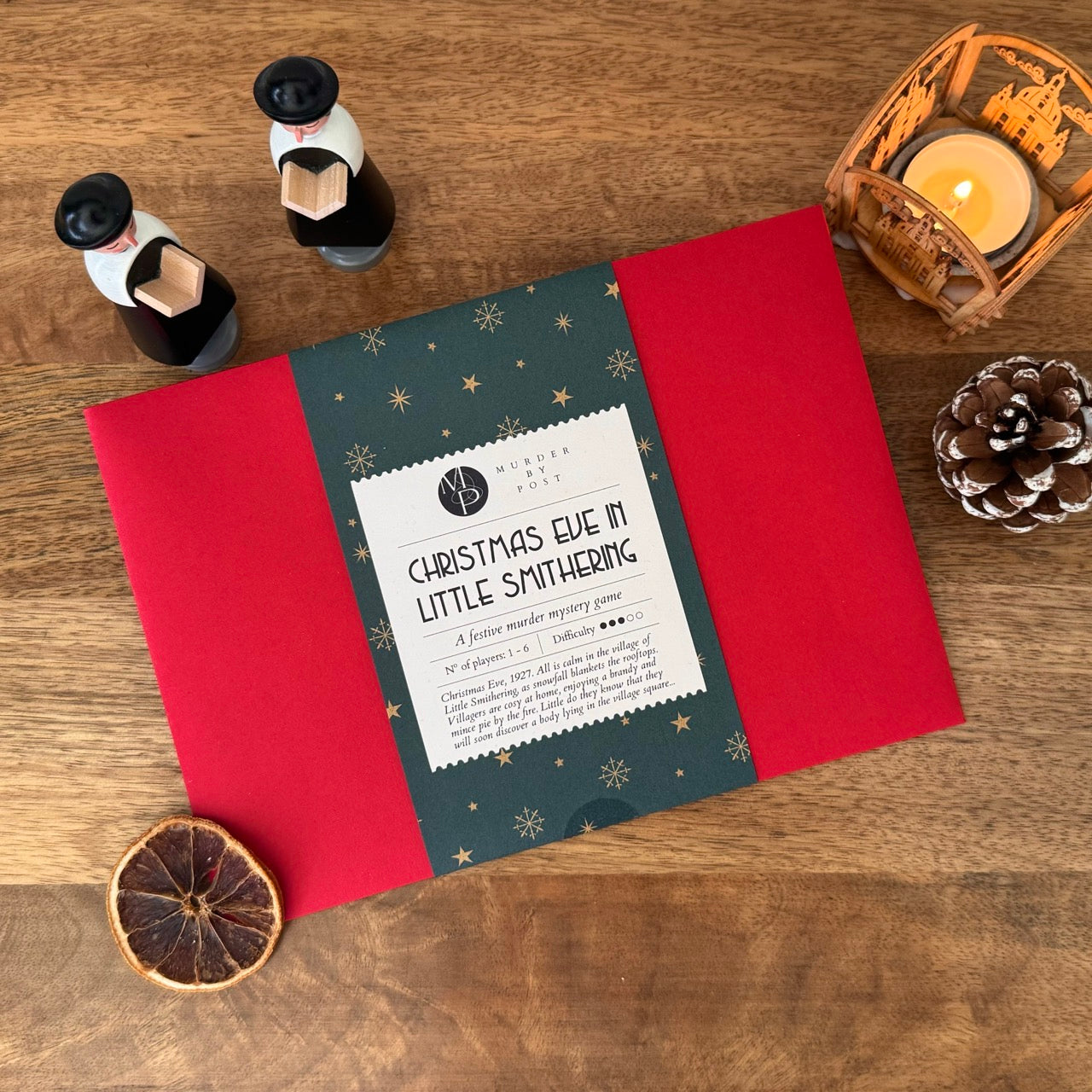 Christmas-themed murder mystery game with red and green design on a wooden surface with decorative items.